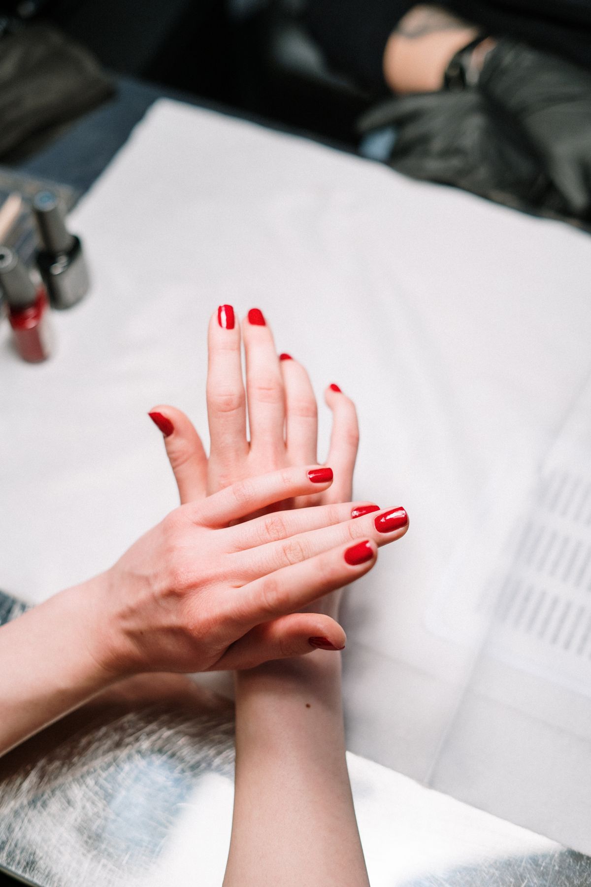 Professional hand treatment features a stylish red manicure at a modern nail salon.