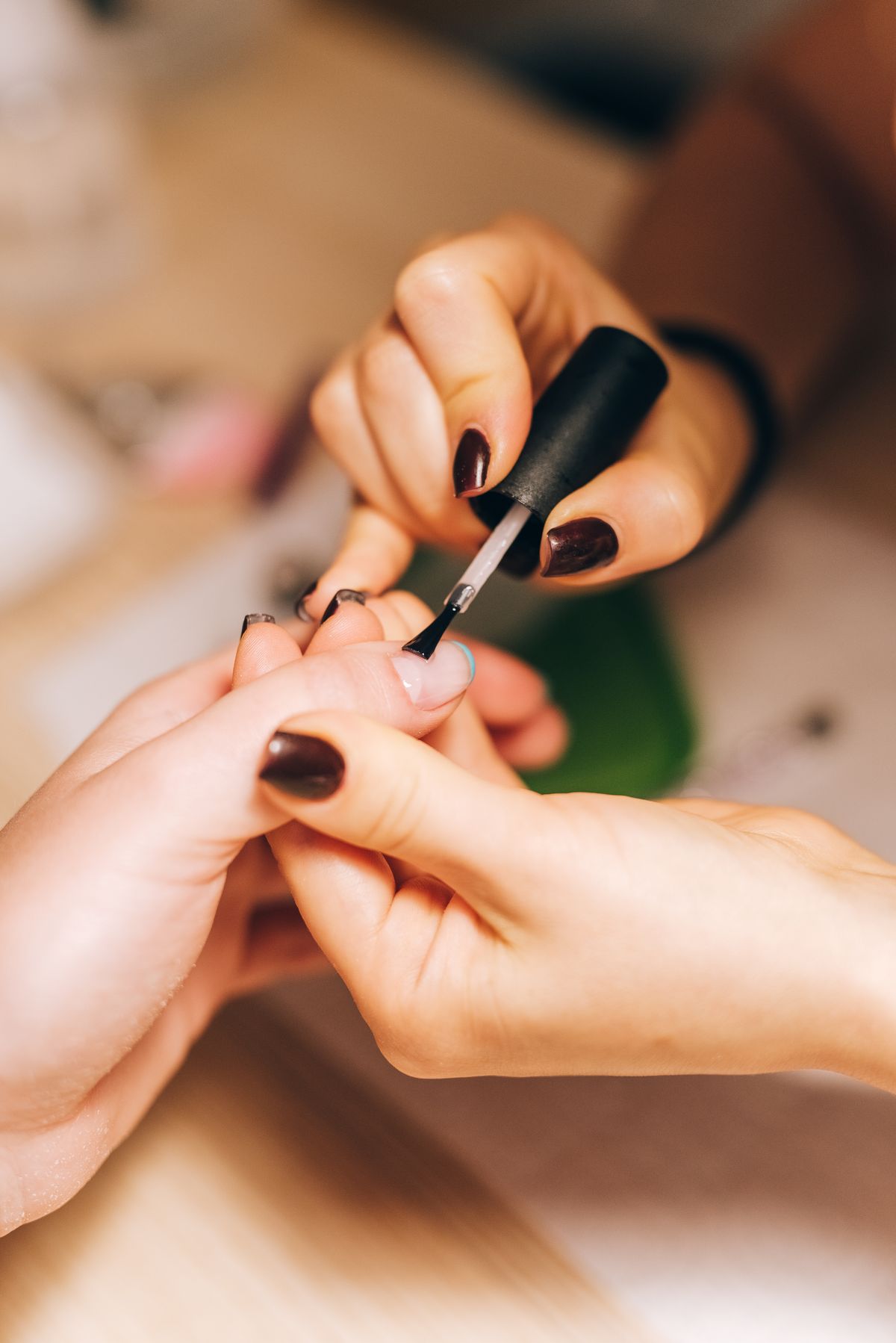 Close-up of a manicurist applying nail polish during a professional manicure session.