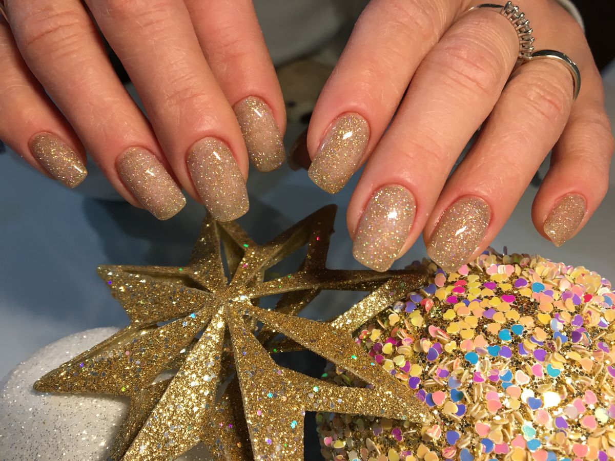 Elegant gold-glittered nails with star decorations, perfect for festive occasions.